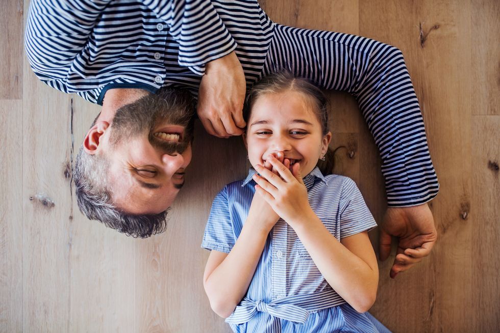 top view of mature father and small daughter lying on floor indoors at home