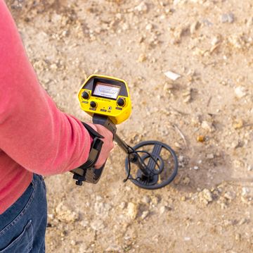 top view of person using a metal detector to find objects in the countryside during a sunny day with copy space right