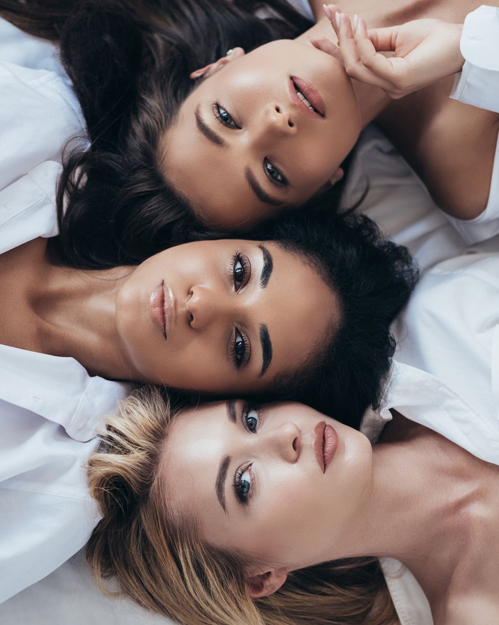 top view of three attractive multiethnic women looking at camera