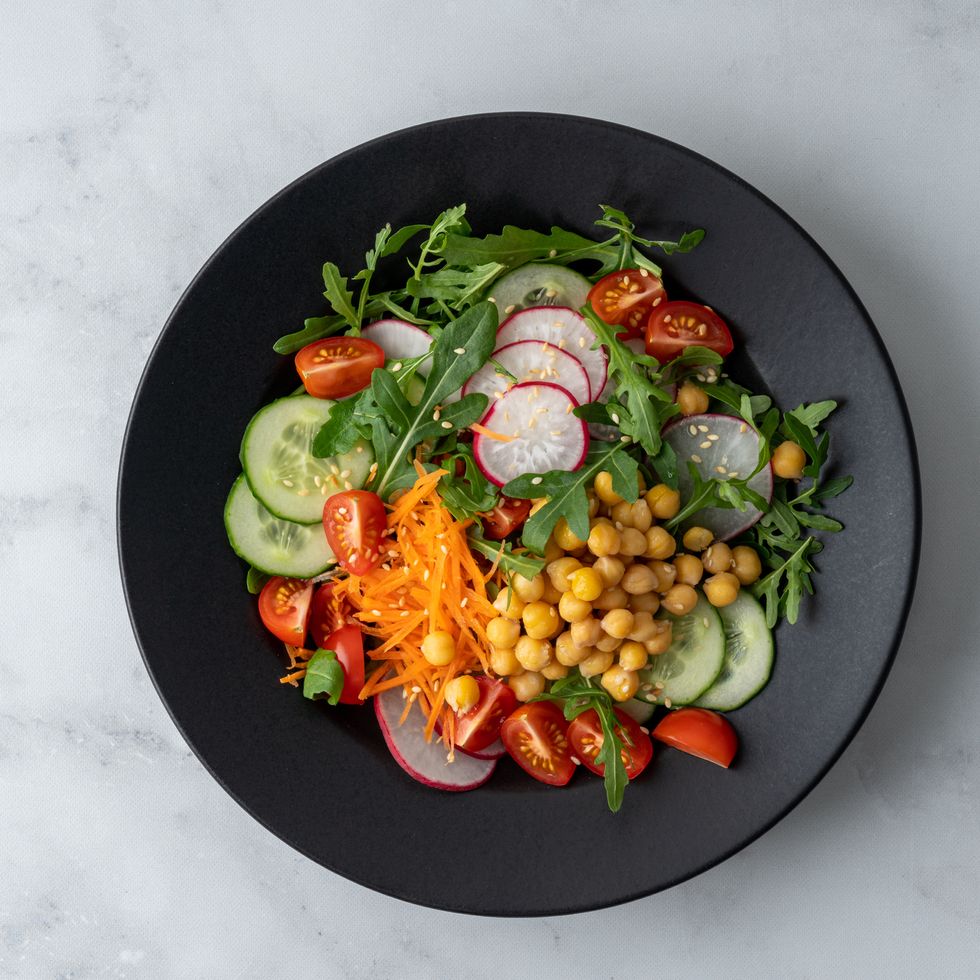 top view of vegetarian fresh salad with tomatoes, cucumbers, carrots, redishes, aragula, chickpeas