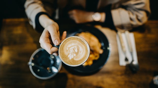 Top view of young woman having a relaxing time enjoying meal with coffee in a cafe