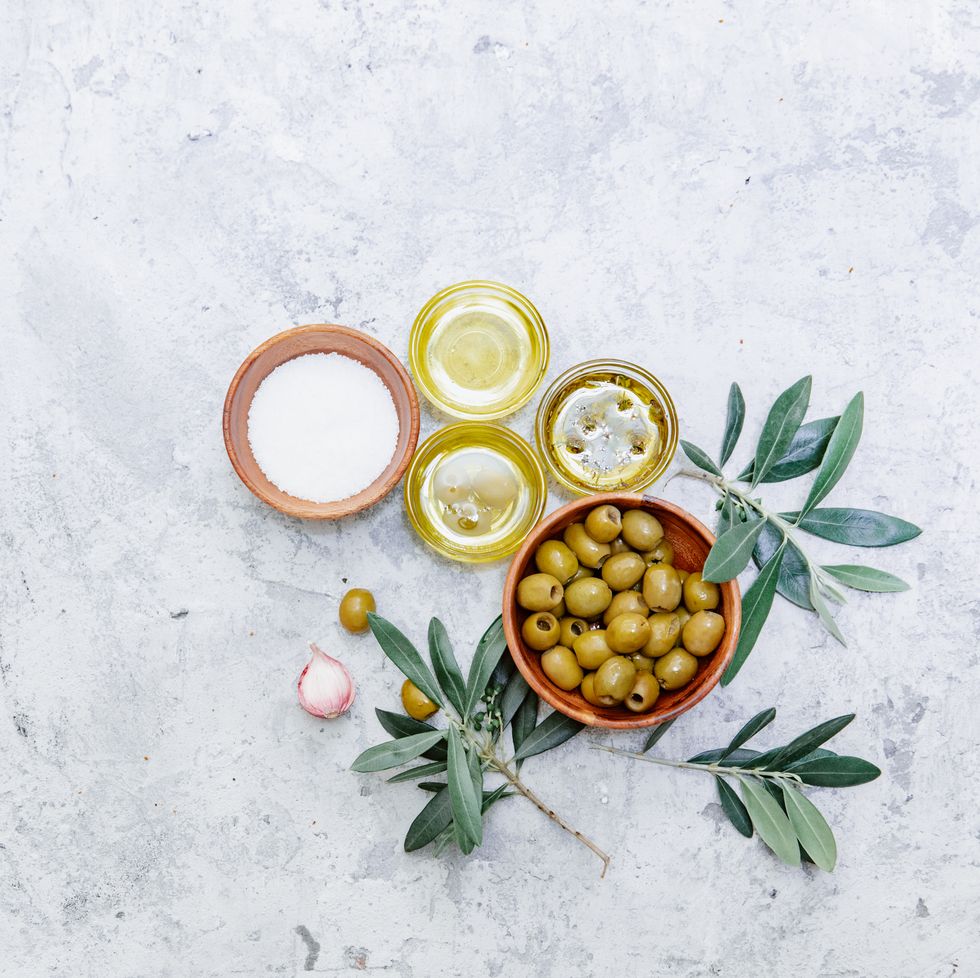 top view organic olive oil, olives, fresh toast bread and olive branch on white background, space for text, flat lay