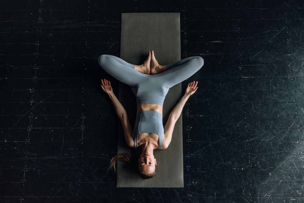 top view woman doing yoga while lying on the floor
