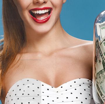 woman smiling and wearing red lipstick while holding a jar of money