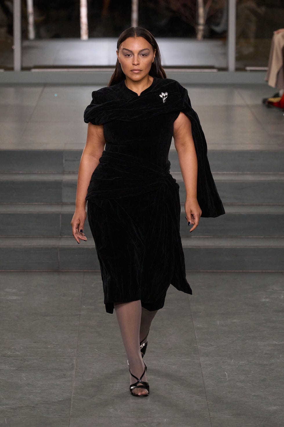 Model walking down the runway in a stylish black dress Model walking down the runway in a stylish black dress