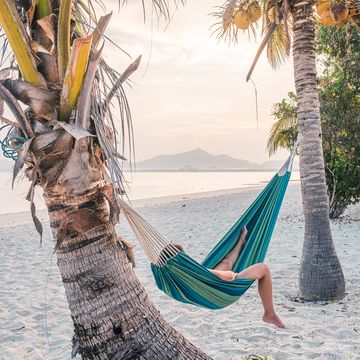 tourist lying on hammock on a tropical beach, thailand