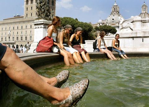 Tourists refresh their feet in a fountai