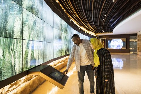black man and hijabi woman at a museum using a touchscreen