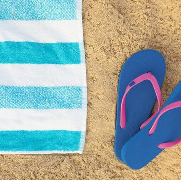 towel and blue sandals on beach background.