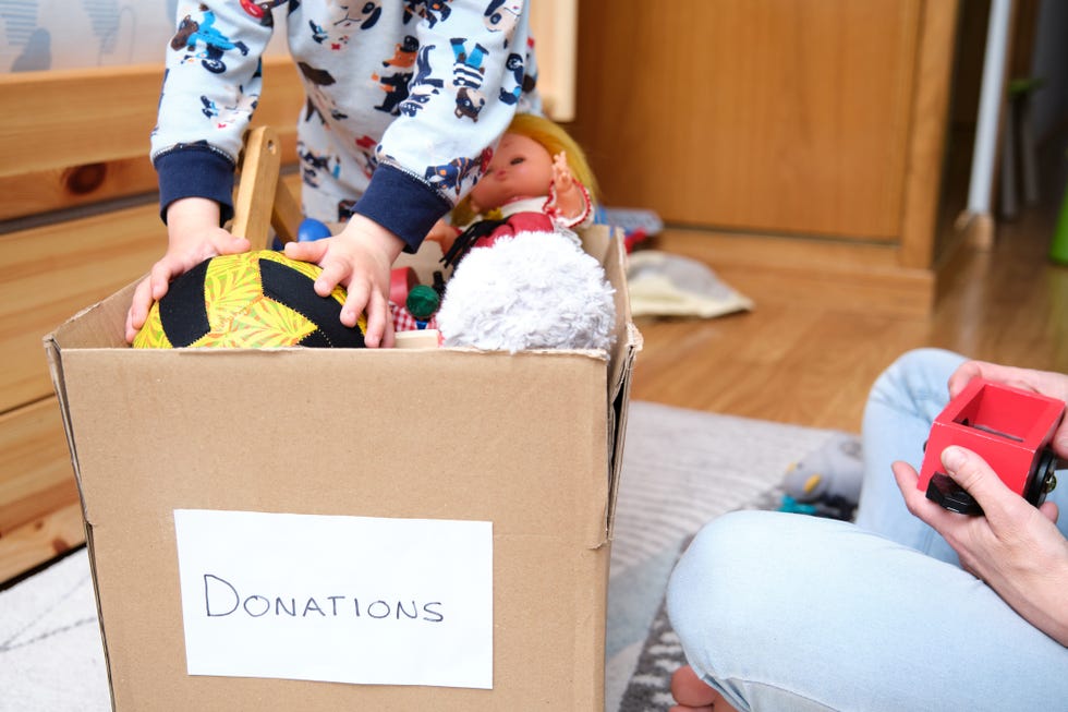 little boy pouring toys into a box for donation