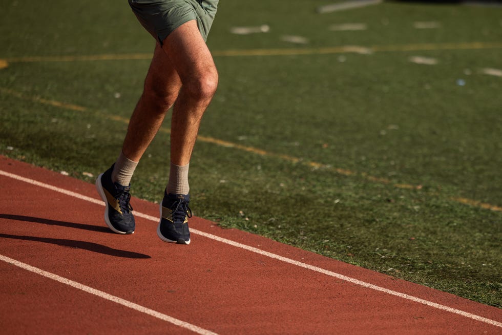 a person running on a track with a focus on their legs