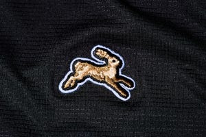 the tracksmith logo on black fabric