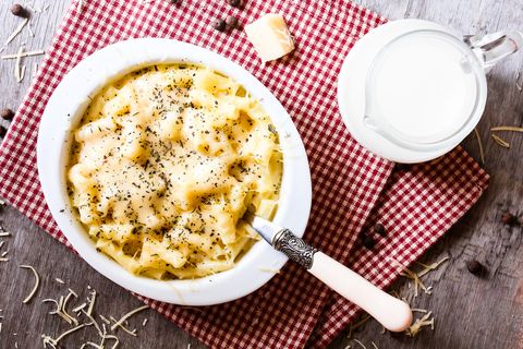 a white bowl of baked macaroni and cheese on a red and white checked cloth