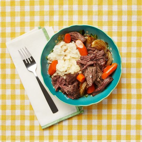 traditional passover food dishes pot roast in blue bowl with mashed potatoes and carrots yellow checkered linen