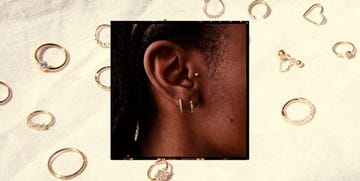 tragus piercing guide 2025. model's ear with tragus piercing, background multiple small gold hoop earrings