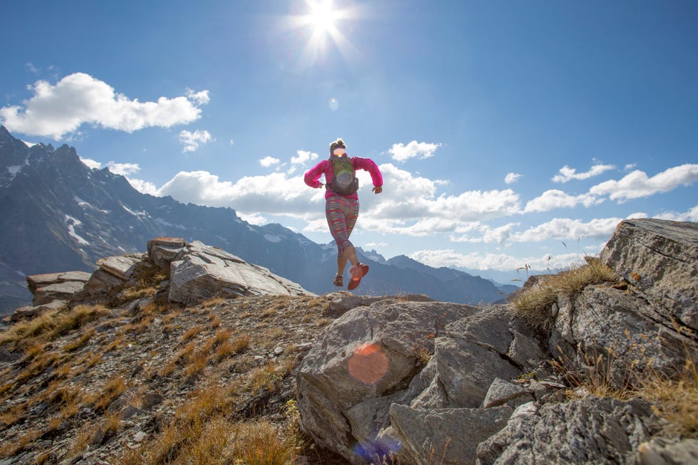 trail runner ascends high mountain ridge