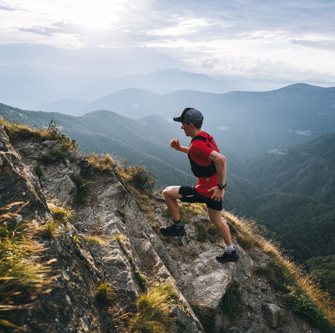 trail runner ascends mountain trail, through alpine meadow