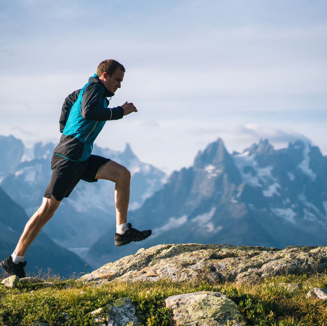 trail runner bounds along mountain meadow in the morning