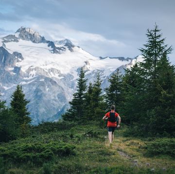 trail runner bounds along mountain trail