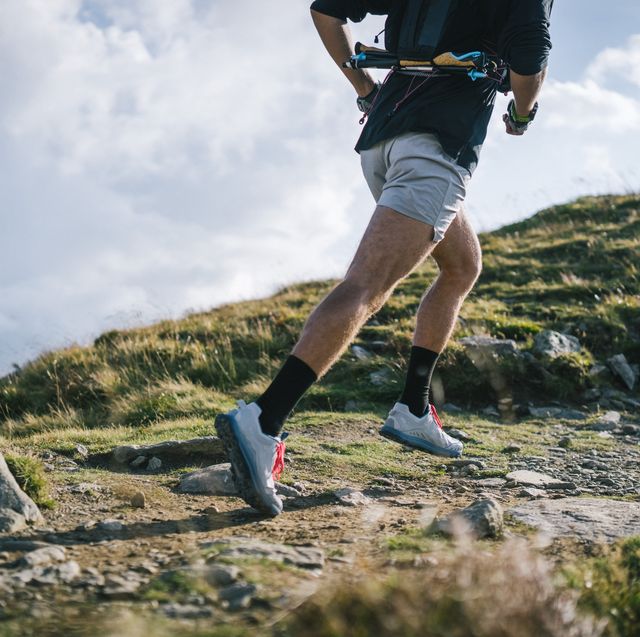 trail runner bounds along mountain trail