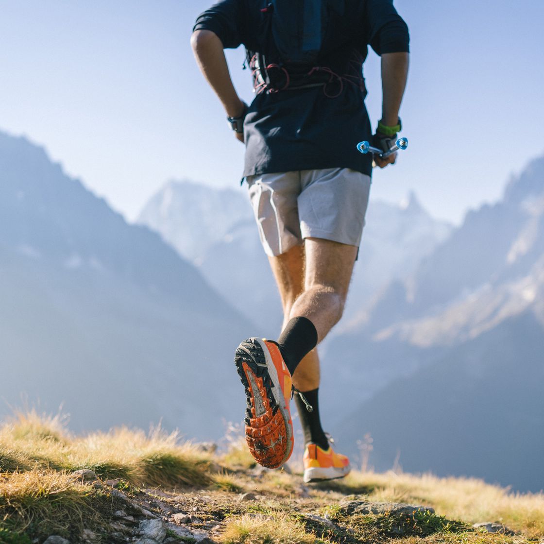 trail runner bounds along mountain trail