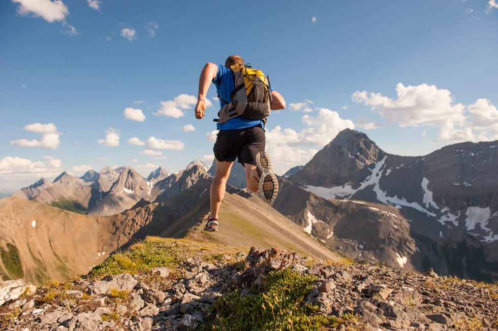 trail runner in mid air stride, on mountain ridge