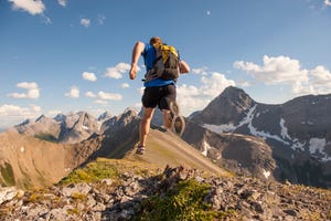 trail runner corriendo con una mochila en mitad de dos montañas