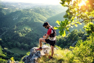 trail runner in mountains, checking smartwatch