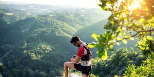 trail runner in mountains, checking smartwatch