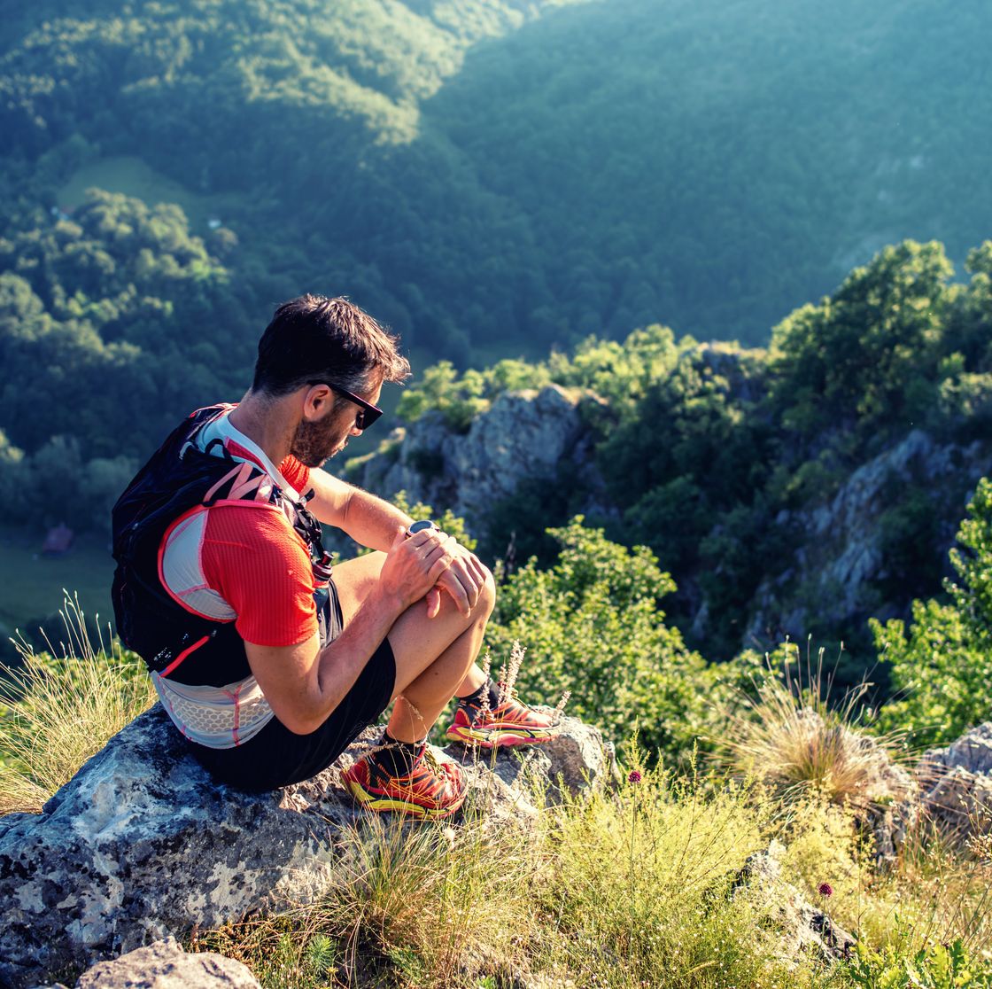 trail runner in mountains, checking smartwatch