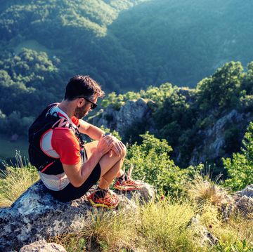 trail runner in mountains, checking smartwatch