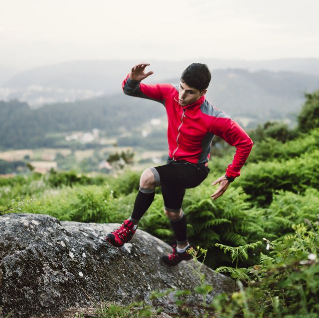 trail runner man training in nature, on a rock