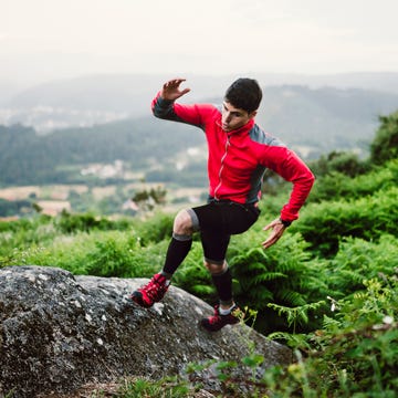 trail runner man training in nature, on a rock