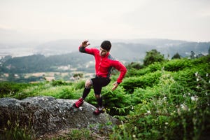 trail runner man training in nature, on a rock