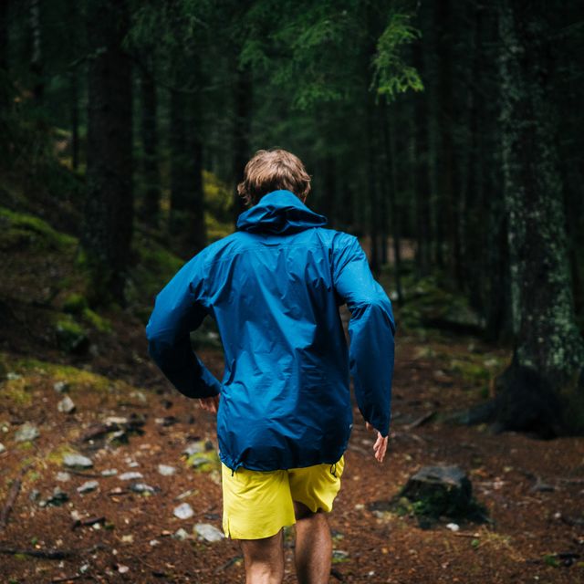 trail runner runs through dark forest in the rain
