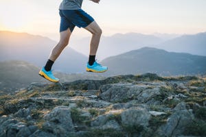 trail runner scrambles up mountain ridge