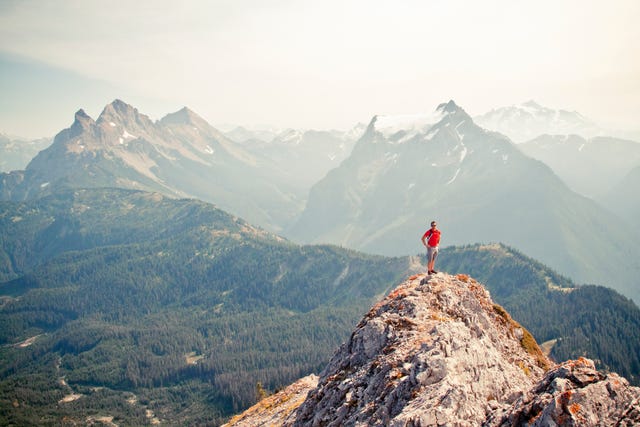 trail runner stands on the airy summit of a rocky mountain ridge