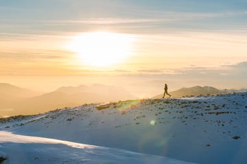 trail runner traverses high ridge above valley