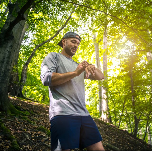 trail runner with smart watch in green forest