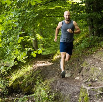 trail runner with smart watch in green forest
