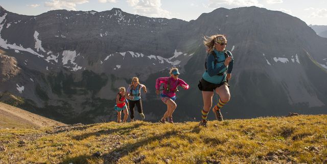 Trail runners in mid air stride towards mtn summit
