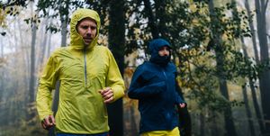 trail runners run through forest on rainy day