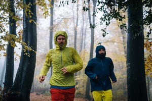 trail runners run through forest on rainy day