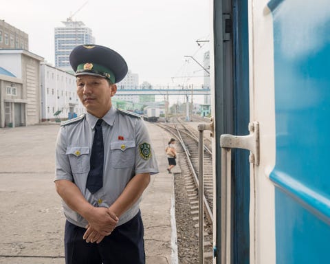 Op het perron van het station van Pyongyang staat een spoorwegmedewerker