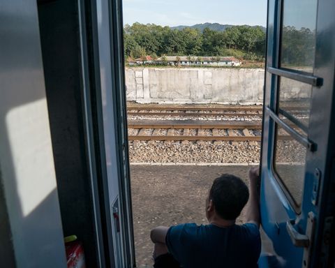 Op weg van Pyongyang naar Rason kijkt een passagier vanuit de trein uit over de omgeving