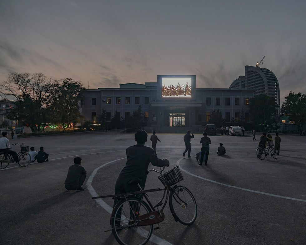 Het centrale plein van Rason wordt in de avondschemering verlicht door een videoscherm