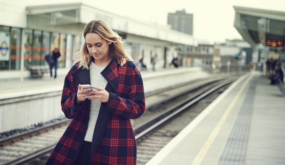 a woman holding a phone at a train station