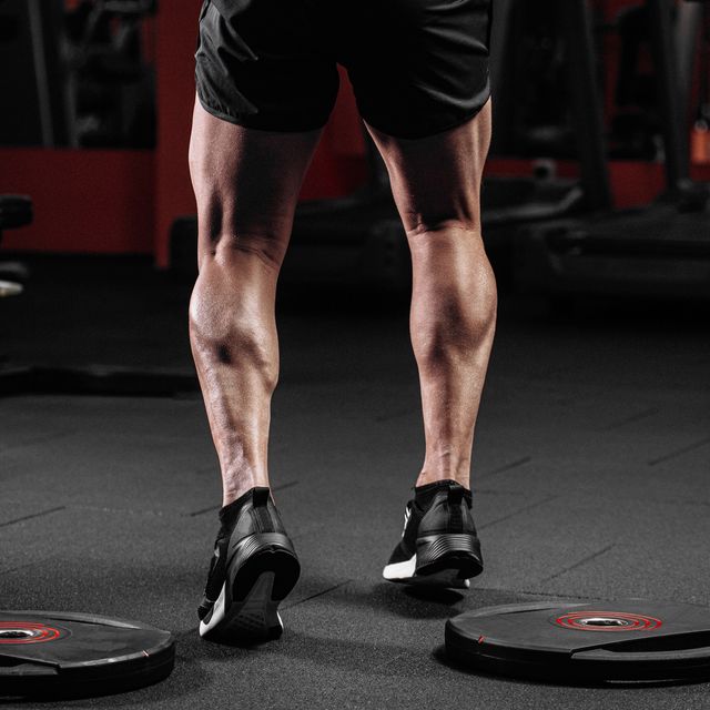 trained man's legs with muscular calves in sneakers in fitness training gym