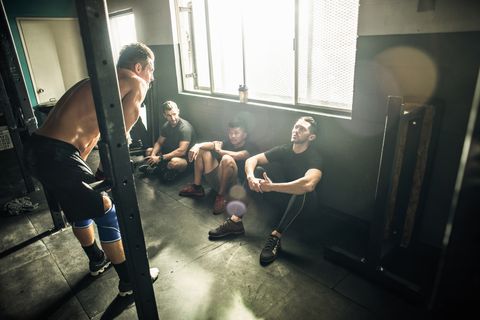 Trainer talking to group of men in gymnasium