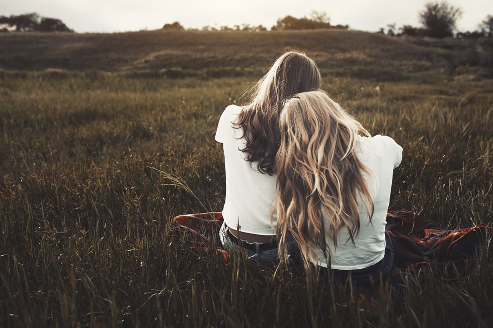 Tranquil teenage sisters in white t-shirts in rural field